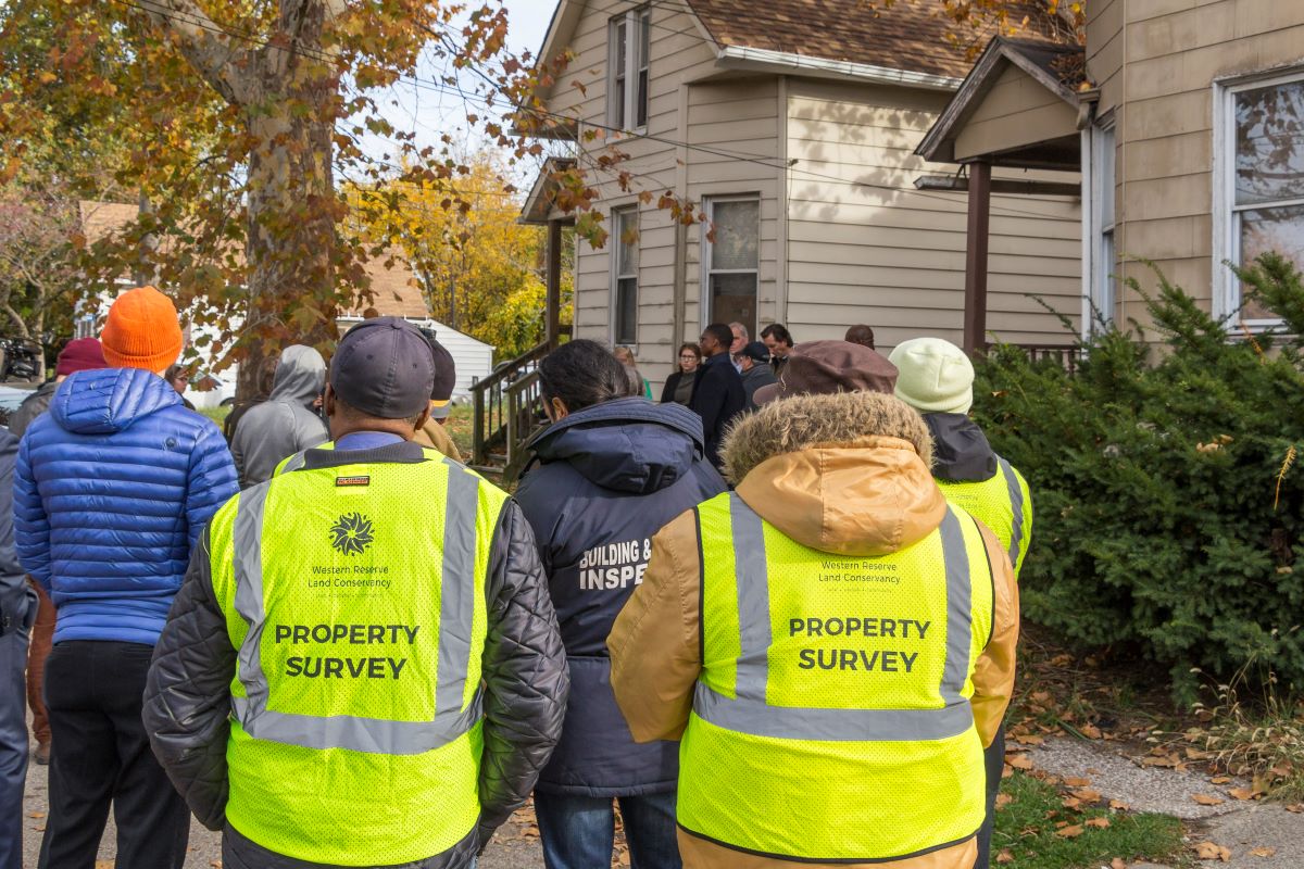 Two city workers wear bright yellow vests with the words 